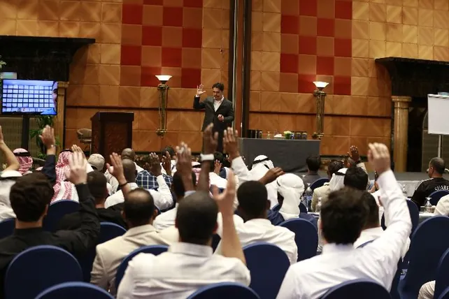 الحضور يرفعون أيديهم في تفاعل مع المدرّب